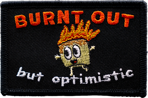 Embroidered patch with cartoon character and text 'BURNT OUT but optimistic' on a black background