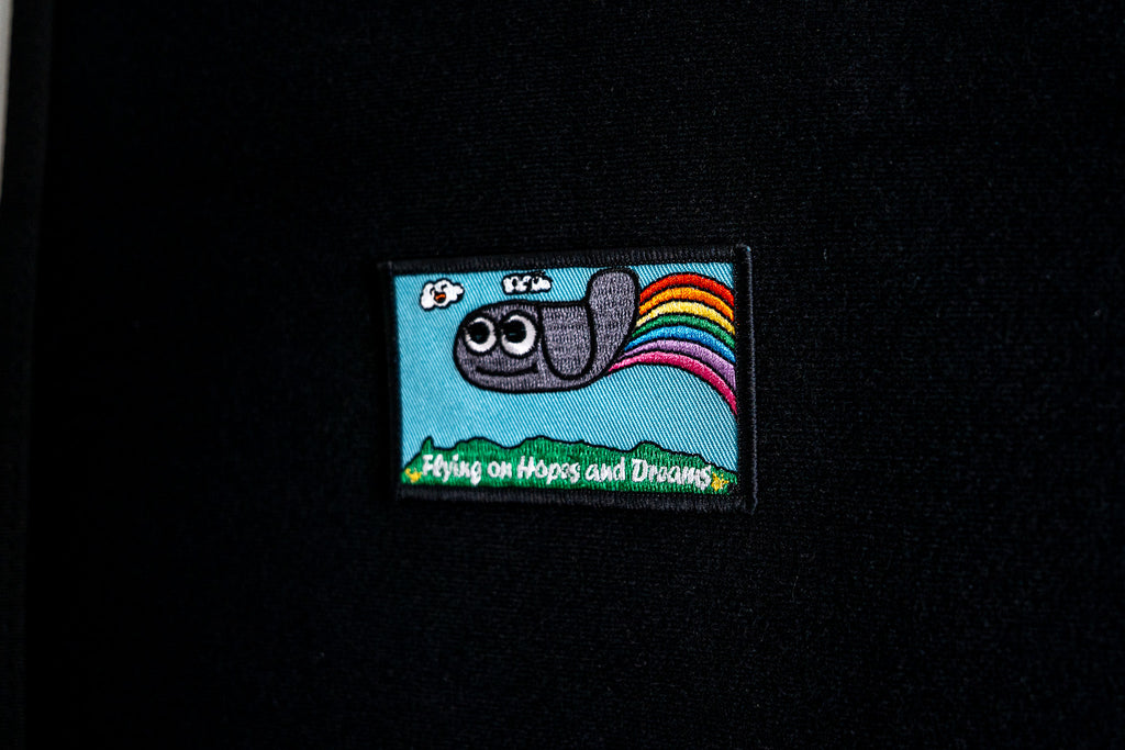 Embroidered patch with a cartoon character and rainbow on a black background