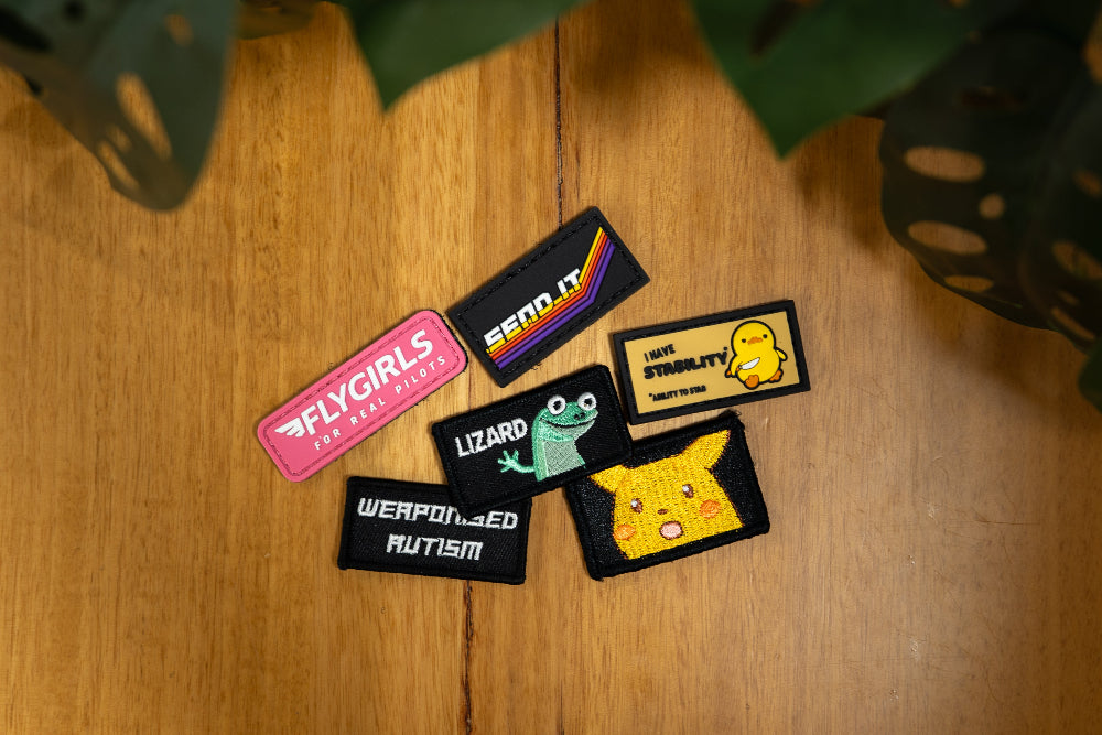 Collection of colorful patches on a wooden surface with plants in the background