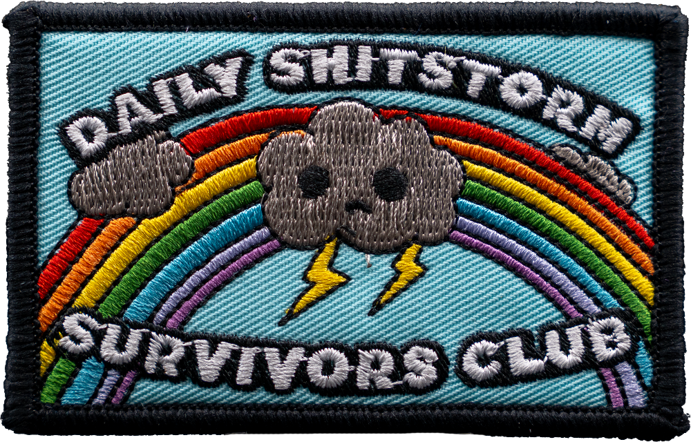 Embroidered patch with rainbow, cloud, and text 'Daily Shitstorm Survivors Club' on a blue background