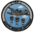 Embroidered patch with airplane and parachuting figures on a blue background